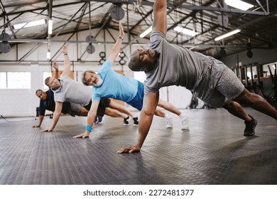 People, fitness and side plank in class with personal trainer for workout, stretching exercise or training. Diverse group in warm up stretch session with coach for cardio wellness or balance on floor - Powered by Shutterstock