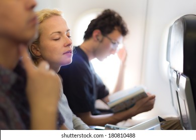 People Flying By Plane. Interior Of Airplane With Passengers Killing Time On Their Seats.