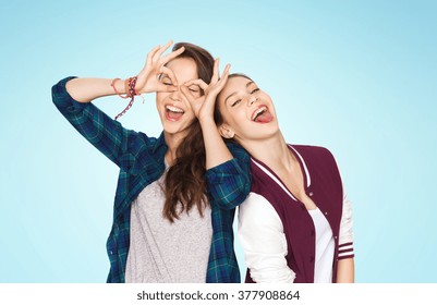 People, Friends, Teens And Friendship Concept - Happy Smiling Pretty Teenage Girls Having Fun And Making Faces Over Blue Background