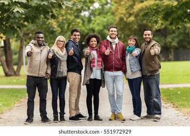 people, friendship, communication and international concept - group of happy friends showing thumbs up at autumn park - Powered by Shutterstock