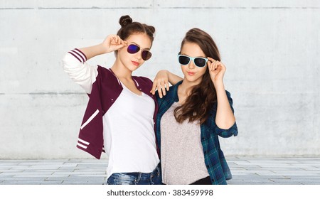 people, friendship, fashion, summer and teens concept - happy smiling pretty teenage girls in sunglasses over urban street background