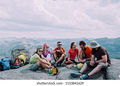 People friendship hangout traveling destination camping concept. Group of six hungry hikers travelers in sportswear relaxing and having snacks after hiking at top of mountain. - Powered by Shutterstock