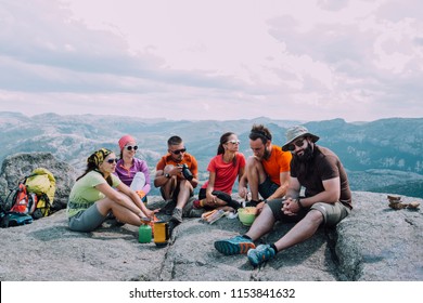 People friendship hangout traveling destination camping concept. Group of six hungry hikers travelers in sportswear relaxing and having snacks after hiking at top of mountain. View with dramatic sky. - Powered by Shutterstock