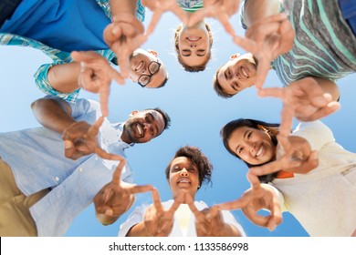 People, Friendship And International Concept - Group Of Happy Smiling Friends Outdoors Standing In Circle And Showing Peace Hand Sign