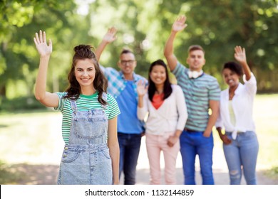 people, friendship and international concept - happy smiling woman and group of happy friends waving hands outdoors