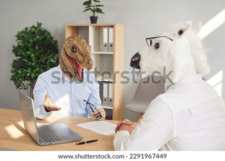 People with funny animal heads at bizarre job interview. Man wearing dinosaur mask sitting at office table with HR manager in horse mask, answering questions and telling about his work experience