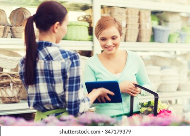 People, Gardening, Shopping, Sale And Consumerism Concept - Happy Gardener With Tablet Pc Helping Woman With Choosing Flowers At Flower Shop