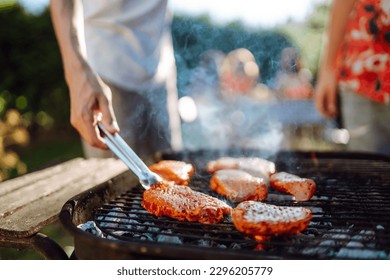 Сompany of people gathered for barbecue in summer garden. Friends grill meat, have fun, relax. Сoncept of lifestyle, holidays, weekends. Picnic and barbecue. - Powered by Shutterstock