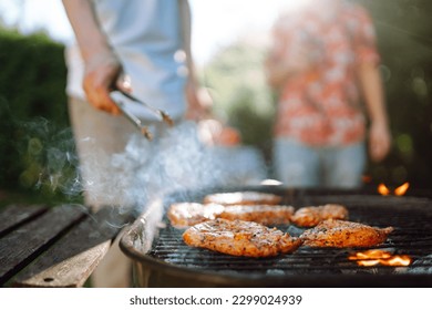 Сompany of people gathered for barbecue in summer garden. Friends grill meat, have fun, relax. Сoncept of lifestyle, holidays, weekends. Picnic and barbecue. - Powered by Shutterstock