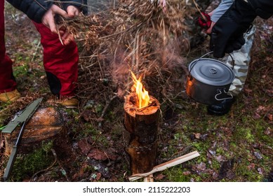 People are going to cook food in a pot on Swedish Fire Log. Burning a Swedish candle, torch in winter evening.