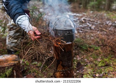People are going to cook food in a pot on Swedish Fire Log. Burning a Swedish candle, torch in winter evening.