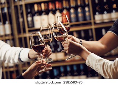 People in good mood clink glasses, celebrating together, photo focus on hands woman and man tasting degustation different types of wine, alcohol beverage to relax, bottles on shelves on background - Powered by Shutterstock