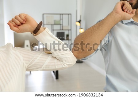 People greeting each other by bumping elbows instead of handshake in office, closeup