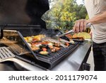 People grilling fish and corn on a modern grill outdoors at sunet, close-up. Cooking food on the open air