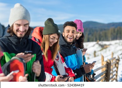 People Group With Snowboard Ski Resort Snow Winter Mountain Cheerful Friends Cahtting Online Smart Phone Sitting On Wooden Hence