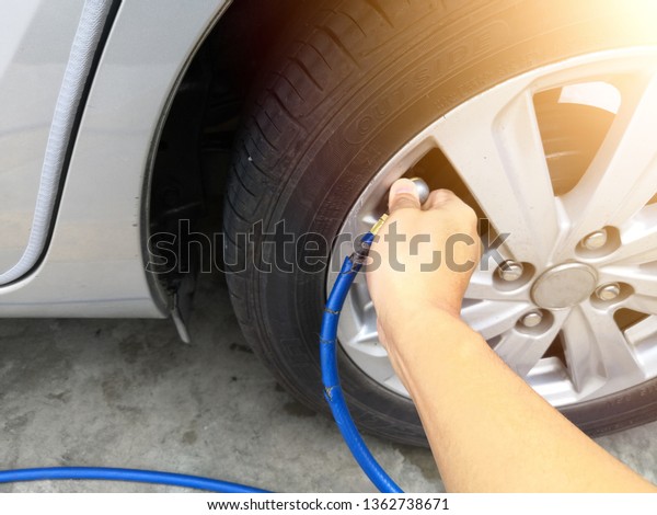People hand are filling the tire pressure\
on the car wheel from automatic air filler at filling station.Copy\
Space.Safe driving or driving safety\
concept.