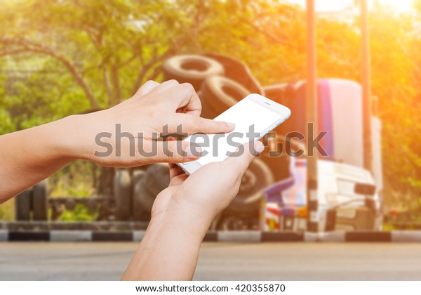 people hand hold and touch screen smart phone\
on overturned truck accident\
background