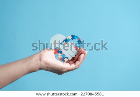 People hand holding jigsaw puzzle, Color puzzle symbol of awareness for autism spectrum disorder family support. Autism World Awareness Day.	
