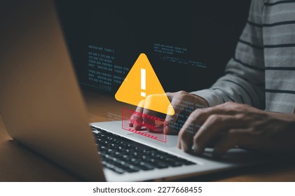 People hand using smartphone and computer laptop that show warning sign after got attack by malware from hacker that commit cyber crime or software crash to cause an error, network malfunction. 