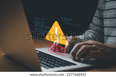 People hand using smartphone and computer laptop that show warning sign after got attack by malware from hacker that commit cyber crime or software crash to cause an error, network malfunction. 