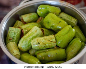 People hands are preparing food. Red Peppers, yellow tomatoes, white zucchini and grape leaves stuffed with minced meat. - Shutterstock ID 2310742957