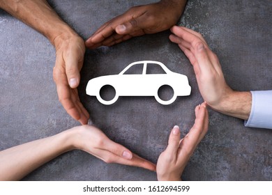 People Hands Protecting Cutout Car Shape At Desk