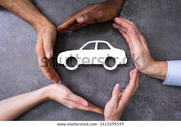 People Hands\
Protecting Cutout Car Shape At\
Desk
