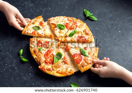People Hands Taking Slices Of Pizza Margherita. Pizza Margarita and  Hands close up over black background.