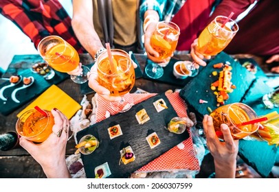 People hands toasting multicolored spritz drinks - Trendy friends having fun together drinking cocktails on happy hour at bar buffet - Social gathering party time concept on hipster orange filter