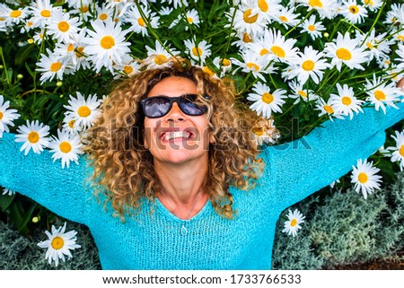 People and happiness concept lifestyle with happu and cheerful adult beautiful caucasian young woman smile with green and coloured daisies background - leisure activity and park outdoor