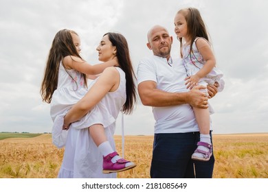 People are having fun.The concept of a friendly family.Mom, dad and daughters hug in a wheat field.Cute beautiful children.Happy family resting in summer park.Summertime and vacation concept.