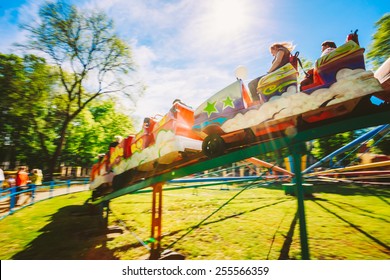 People Having Fun On Rollercoaster In The Park. Photo With Zoom Blur For Motion Effect