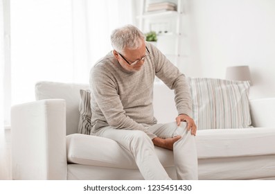 people, health care and problem concept - unhappy senior man suffering from knee ache at home - Shutterstock ID 1235451430