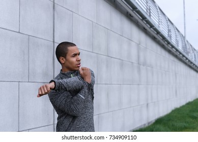 People, health, wellbeing, motivation, strength, sports and fitness concept. Candid shot of attractive self confident young Afro American sportsman doing physical exercises outdoors, stretching arms
