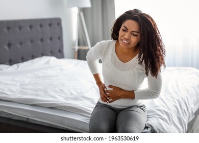 People, Healthcare And Health Problem Concept. Portrait Of Upset Sick Young Black Woman Suffering From Acute Pain In Right Side, Sitting On Bed At Home, Free Copy Space. Abdomen Liver Pain