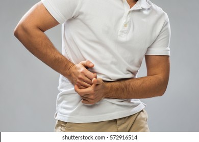 people, healthcare and health problem concept - close up of man suffering from stomach ache over gray background