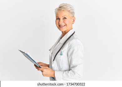 People, Healthcare, Medicine And Medical Occupation Concept. Good Looking Confident 50 Year Old Blonde Woman Doctor Wearing White Coat And Stethoscope Holding Clipboard While Making Rounds In Hospital