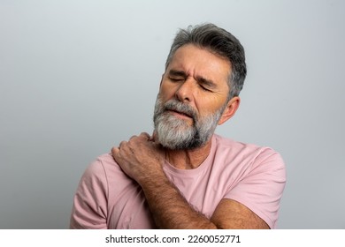 People, healthcare and problem concept - unhappy man suffering from neck or shoulder pain at home. Mature bearded man has shoulder pain. with copy space for text. Man holding his injured shoulder - Powered by Shutterstock