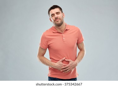 people, healthcare and problem concept - unhappy man suffering from stomach ache over gray background - Shutterstock ID 375342667