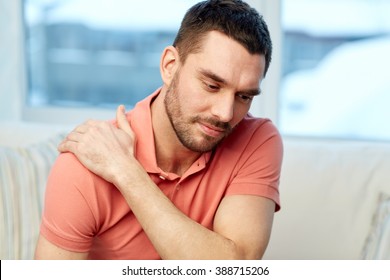 people, healthcare and problem concept - unhappy man suffering from neck or shoulder pain at home