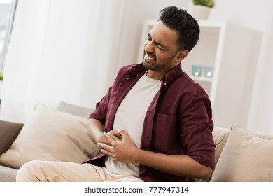 people, healthcare and problem concept - unhappy man suffering from stomach ache at home - Shutterstock ID 777947314