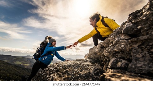 People helping each other hike up a mountain at sunrise - Giving helping hand and teamwork concept - Powered by Shutterstock