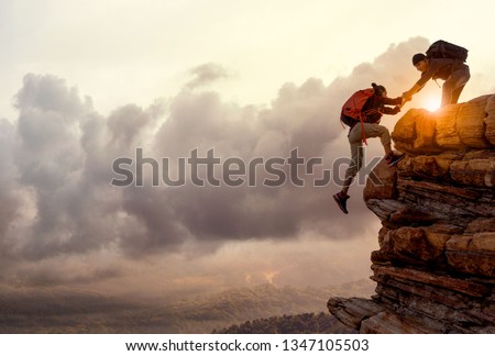 People helping each other hike up a mountain at sunrise. Giving a helping hand, and active fit lifestyle concept.Asia couple hiking help each other.