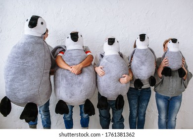 People hiding their faces behind stuffed penguin dolls