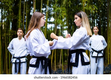 People High Kicks During Training Of Taekwondo Outdoors Bamboo Background.