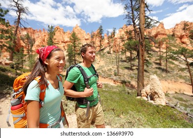 People Hiking - Couple Hikers In Bryce Canyon Walking Smiling Happy Together. Multiracial Couple, Young Asian Woman And Caucasian Man In Bryce Canyon National Park Landscape, Utah, United States.