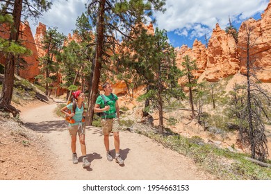 People Hiking - Couple Hikers In Bryce Canyon Walking On Trail Happy With Backpacks. Multiracial Young Asian Woman And Caucasian Man In Bryce Canyon National Park Landscape, Utah, United States.