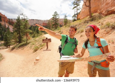 People Hiking Looking At Hike Map In Bryce Canyon. Young Multiracial Couple Of Hikers Navigating And Smiling Happy During Hike In Bryce Canyon National Park Landscape, Utah, USA. Young Woman And Man.