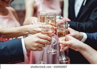 People hold in hands glasses with white wine. wedding party. friends toasting with a champagne above white table