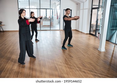 People holding arms in circle while doing taijiquan pose - Powered by Shutterstock